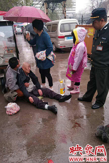 女孩為倒地老人撐傘。