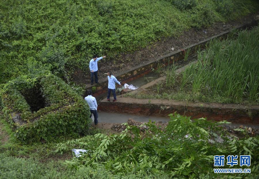 5月18日，工作人員在槽罐車泄漏現(xiàn)場附近的水渠邊查看情況。