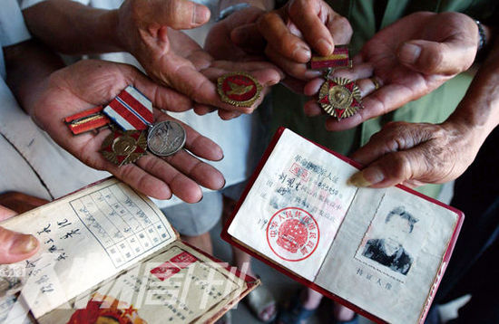 幾位志愿軍老兵展示自己的立功證、傷殘軍人證與勛章