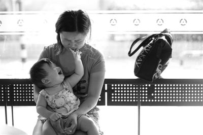 昨日，肯德基京廣中心店門口，姜女士提起跟養(yǎng)父母的關(guān)系時(shí)落淚，懷中9個(gè)月的女兒笑著跟她玩。新京報(bào)記者 薛珺 攝