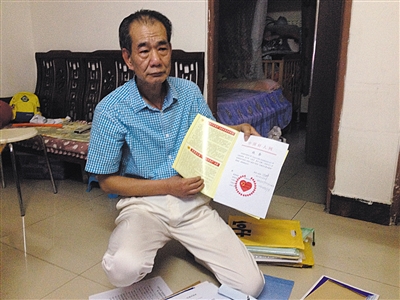 翻出一家網(wǎng)站贈予的“中國好人”證書，區(qū)少坤單膝跪在地上，“你看，我是中國好人啊?！?范春旭 攝