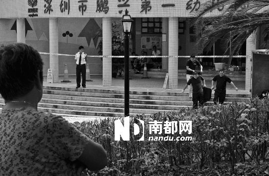→7月19日，鵬興花園第一幼兒園門前，民警在現(xiàn)場(chǎng)進(jìn)行完勘查取證后，園長(zhǎng)和保安的尸體被運(yùn)走。南都記者 徐文閣 攝