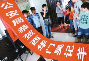 面對警方收繳的條幅，老板楊某也不好意思地用手遮擋臉