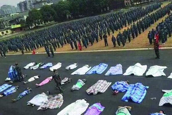 20多名女生躺在瀝青跑道上，身上嚴嚴實實地裹著棉被，接受太陽的照曬。