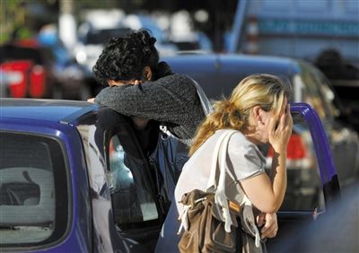 27日，遇難者親友在火災(zāi)現(xiàn)場旁哭泣。