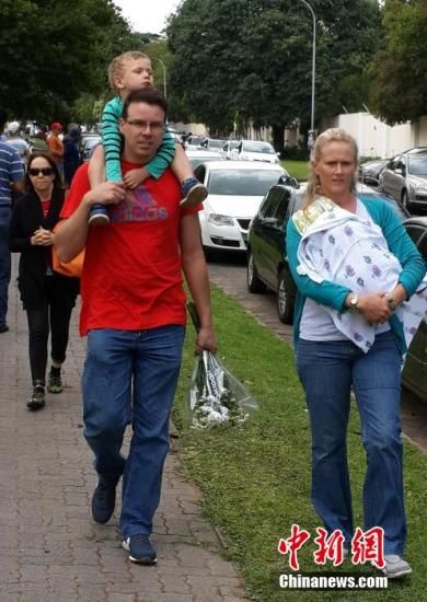 圖為一個(gè)白人家庭，由父母帶著孩子到曼德拉家門外悼念。中新社發(fā) 宋方燦 攝