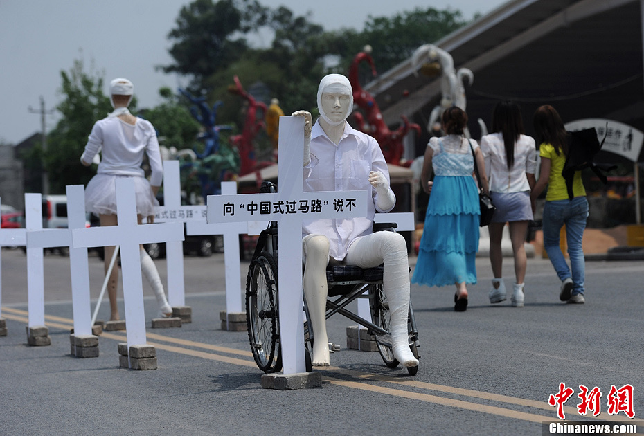 4月16日，重慶市洋人街上擺放著兩個(gè)受了傷的塑料人像“模特”，旁邊十字架上寫著向“中國(guó)式過(guò)馬路”說(shuō)不