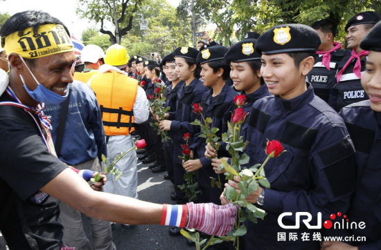 2013年12月03日,曼谷總理府與曼谷警署允許反政府示威民眾進(jìn)入,雙方進(jìn)入暫時“停戰(zhàn)”狀態(tài)迎接泰王生日。曼谷警察總署,女警們手持鮮花送給反政府示威民眾。圖片來源:Manish Swarup/東方IC
