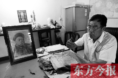 　魏樹紹手拿《物權法講義》手稿，在講訴先祖書寫“物權法”的歷史（相框里就是魏聯(lián)奎）