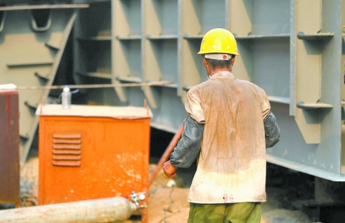 工地上，一建筑工人的衣服被汗水浸透。