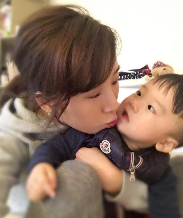 照片中李念狂吻兒子，小寶貝自顧自地玩著。