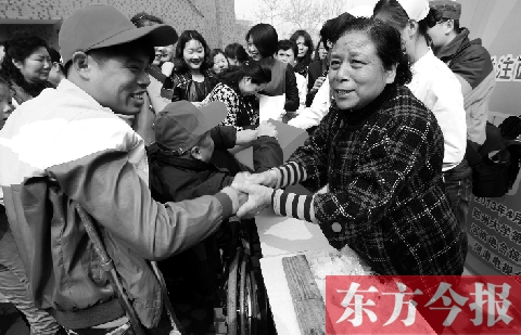 昨日，鄭大四附院的大樓前，“面人鄭”鄭玉芬（右）向前來捐款的殘疾人表示感謝