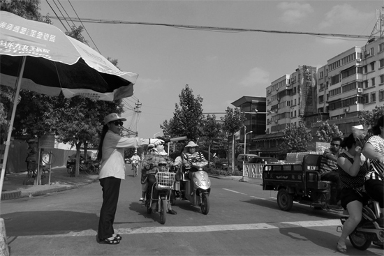 昨日，開封市區(qū)一名協(xié)管員在指揮群眾過馬路