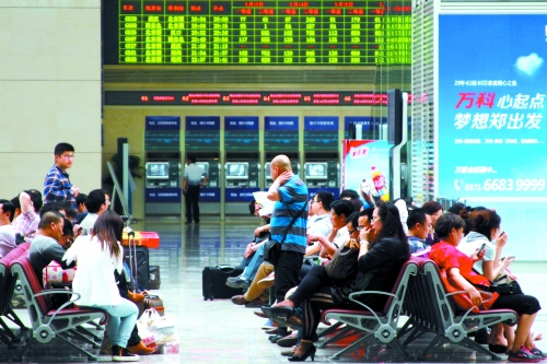 候車大廳溫度很高，一名乘客一手扇風、一手擦汗