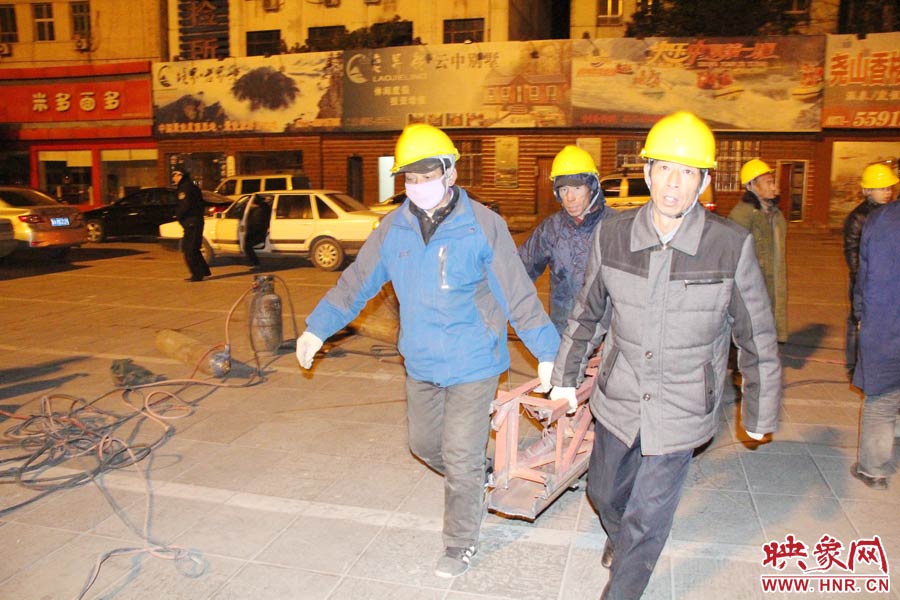 23點(diǎn)56分，第一塊兒廣告牌已經(jīng)分割完畢，地面上的20多名工人將拆除下來(lái)的鋼件撞車運(yùn)走。