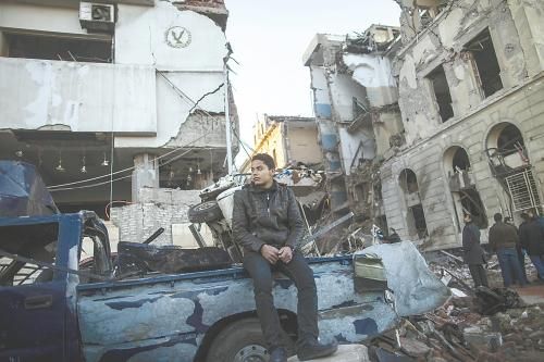 埃及曼蘇拉市警察局24日遭汽車炸彈襲擊，被疑是穆兄會的報復(fù)。圖為一名男子在被炸毀的警察局前。