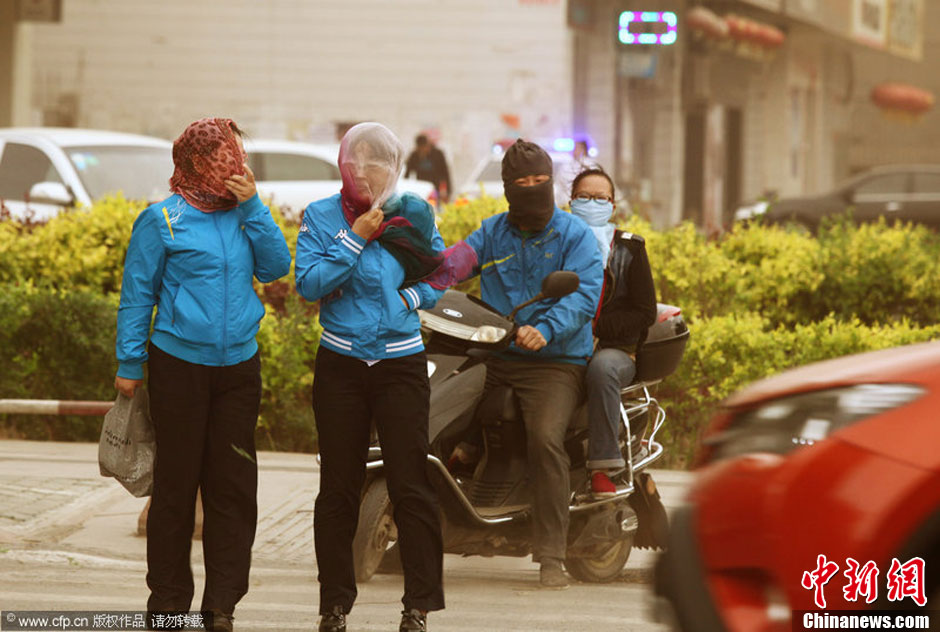 2014年04月23日，新疆維吾爾自治區(qū)吐魯番地區(qū)，市民戴著口罩行走在大風(fēng)沙塵中的吐魯番市街頭。