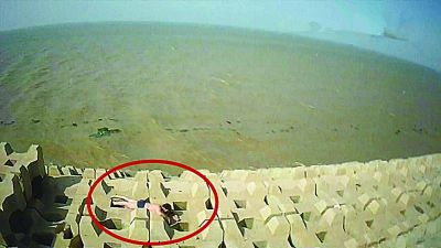 孫正龍游上岸，趴在海邊精疲力盡。