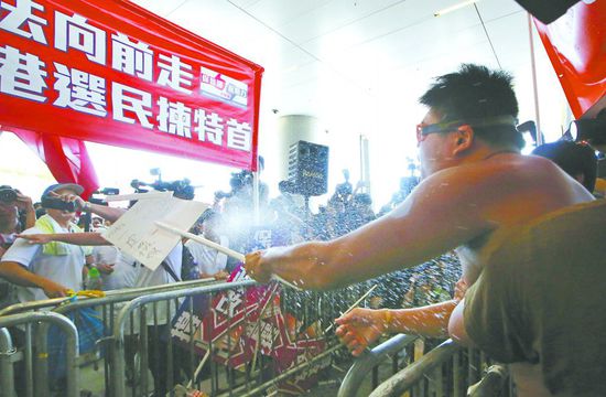 17日，在香港立法會(huì)外，一名反對(duì)政改的男子向支持派人群投擲標(biāo)牌。