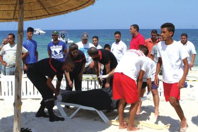 6月26日，在突尼斯蘇塞，救生員和醫(yī)務人員在發(fā)生襲擊事件的海灘運送一名死者的遺體。新華社發(fā)