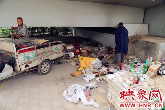 負(fù)責(zé)高架橋下綠化的人員在清理流浪漢留下的垃圾和雜物。