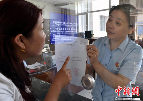 資料圖：2015年5月4日，河北石家莊市橋西區(qū)人民法院立案庭庭長(zhǎng)齊燕正在為立案人辦理相關(guān)手續(xù)，完成整個(gè)過(guò)程只用了5分鐘。當(dāng)日是立案登記制改革首個(gè)工作日，該院共立案36件，立案率達(dá)到90%。中新社發(fā) 翟羽佳 攝