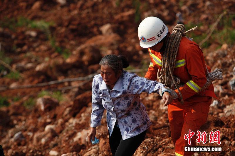 一位消防戰(zhàn)士將一位失去親人的老人扶離滑坡點。