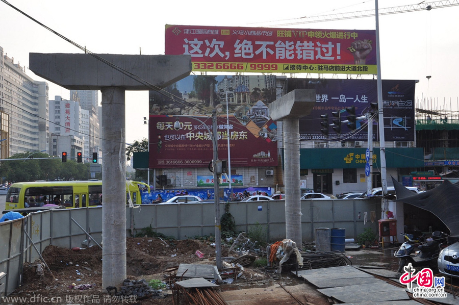 過街天橋一側(cè)的橋樁早已打好,可是對(duì)面的郵政銀行網(wǎng)點(diǎn)依舊在照常營(yíng)業(yè)。