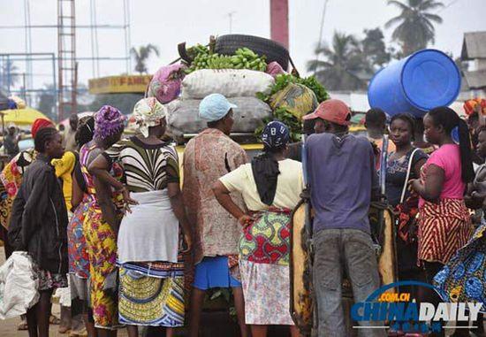 當(dāng)?shù)貢r(shí)間2014年8月14日，利比里亞蒙羅維亞，市場(chǎng)里的商人們圍著一輛汽車(chē)。