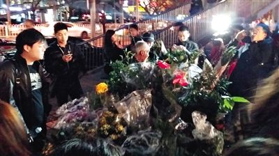 昨晚7時許，三里屯太古里西邊附近一過街天橋旁邊，聞訊而至的網(wǎng)友圍住了賣花老人，爭相買花。 網(wǎng)友“行者橙子”供圖